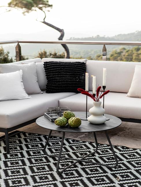 witte outdoor loungebank met zwarte en witte kussen en een outdoor vloerkleed