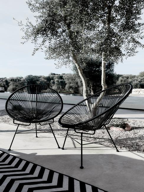 een moderne tuin met zwarte stoelen met outdoor kleed