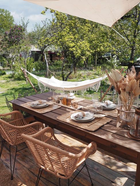 achtertuin ideeën: rieten stoelen met houten tafel