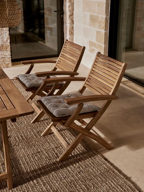 terras met houten stoelen met grijze kussens en rieten kleed