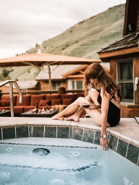 stenen hottub met vrouw in zwart badpak