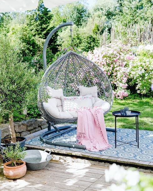 hangstoel in tuin met blauw vloerkleed