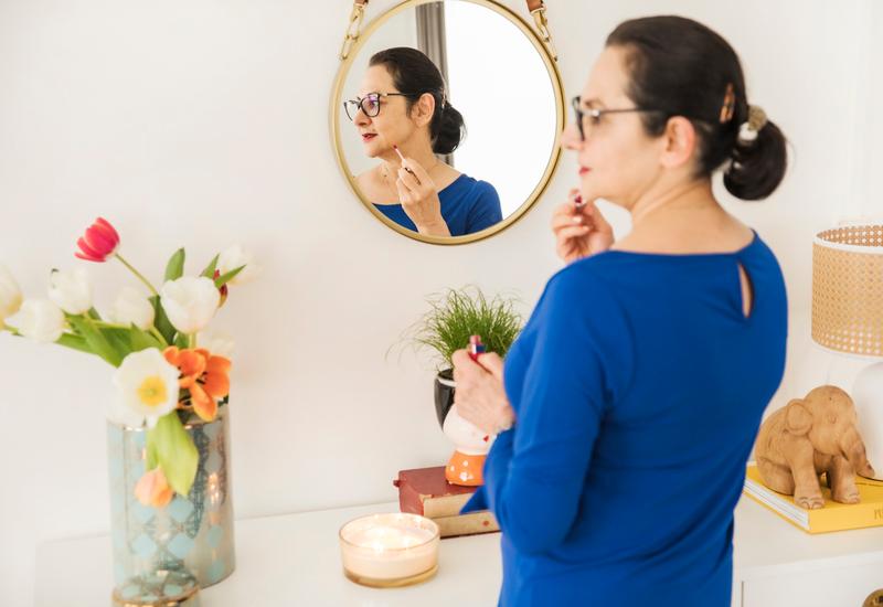 vrouw in een blauwe jurk voor een goude ronde spiegel