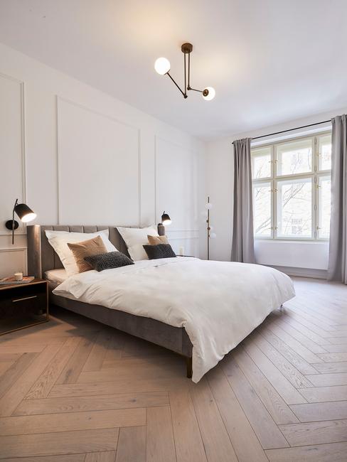 grijze boxspring met zwarte lampen op een houten vloer