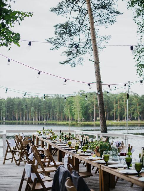 houten tafel en stoelen met gedekte tafel en zwarte lampjes