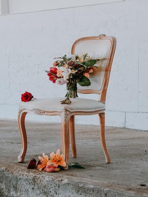 houten stoel met witte kussens en een vaas met bloemen