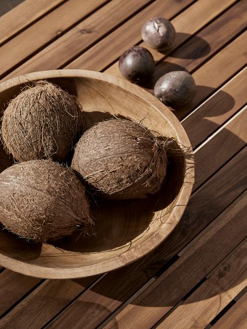 houten tafel met een houten schaal met kokosnoten