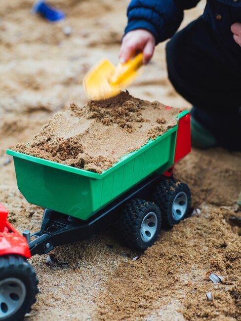 zandbak met speelgoed wagentje voor een kindvriendelijke tuin