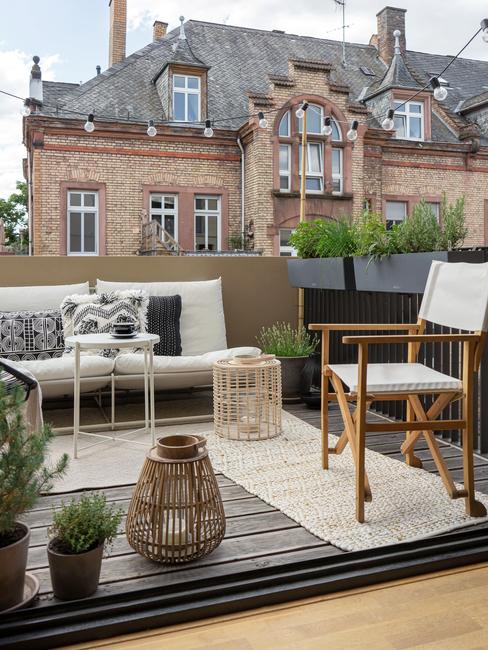 beige bank met zwarte kussens en witte stoel