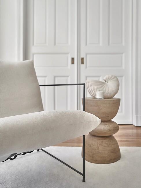 beige stoel met zwarte poten en houten bijzettafel
