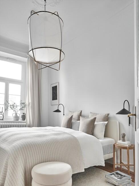 beige bed met witte plafondlamp
