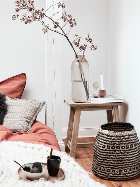 slaapkamer in herfstkleuren met rieten mand en houten kruk