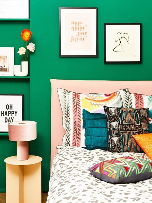 memphis-design: groene muur met een roze boxspring en zwarte fotolijsten