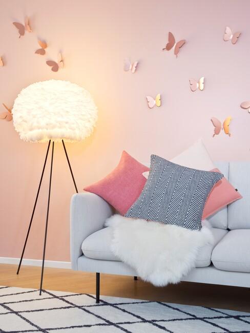 grijze bank met een roze muur en gouden vlinders