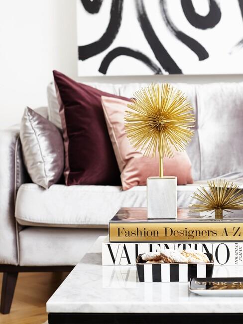 grijze velvet bank met roze kussens en gouden details