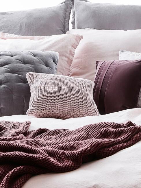mauve kussens op een grijs bed