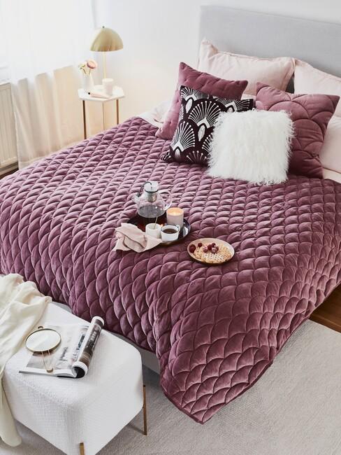Paarse deken over een grijs bed