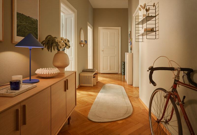 greige muren in hal met houten dressoir en fiets