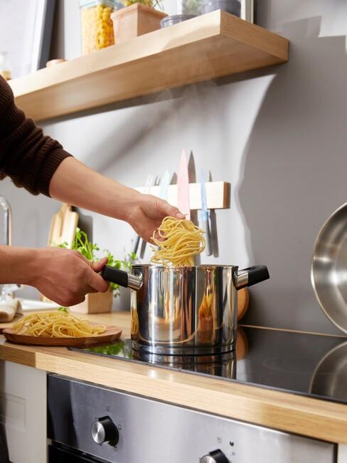 Een pan met pasta en een wit bord