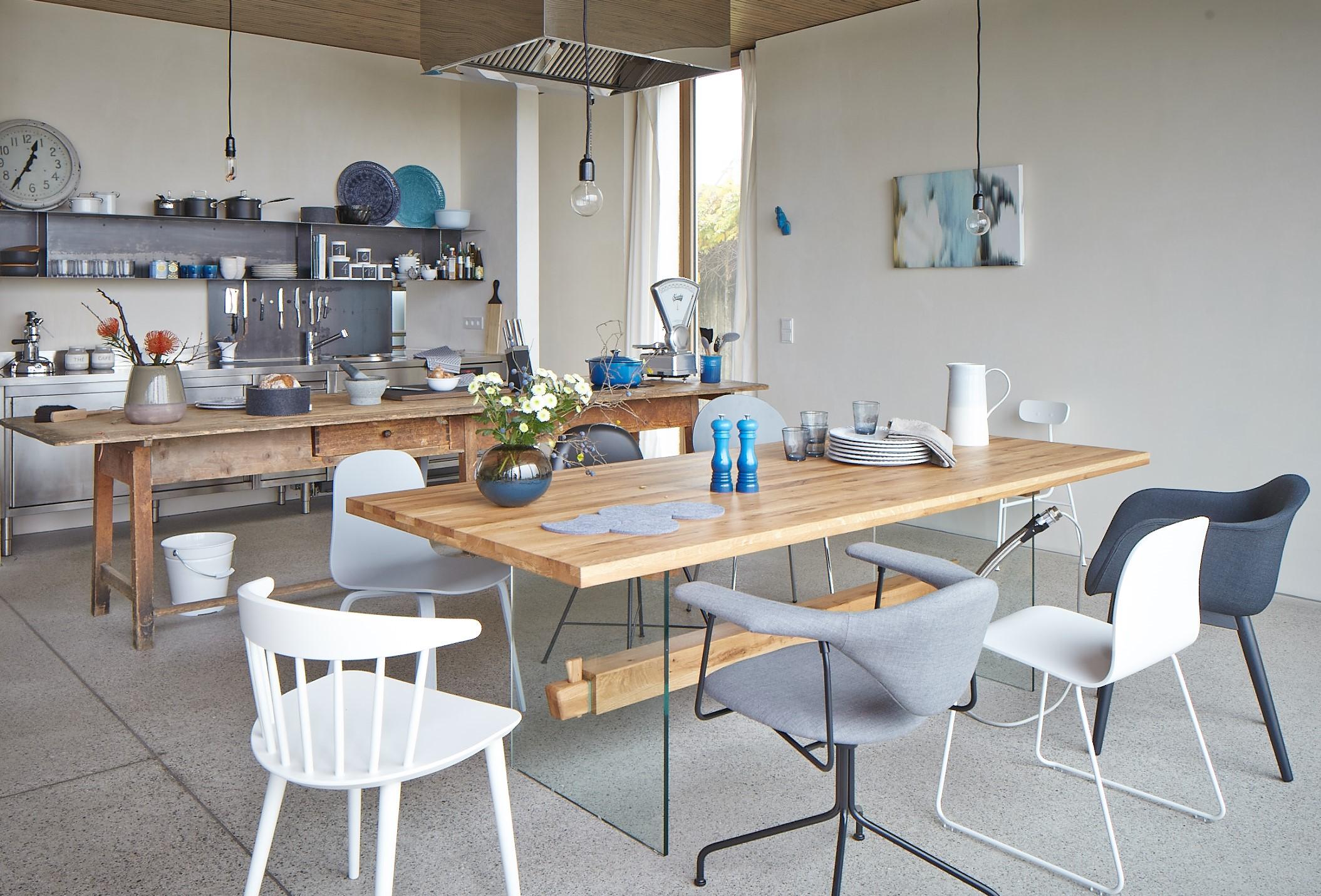 industriële keuken in het roestvrijstaal en houten tafel met witte en grijze stoelen