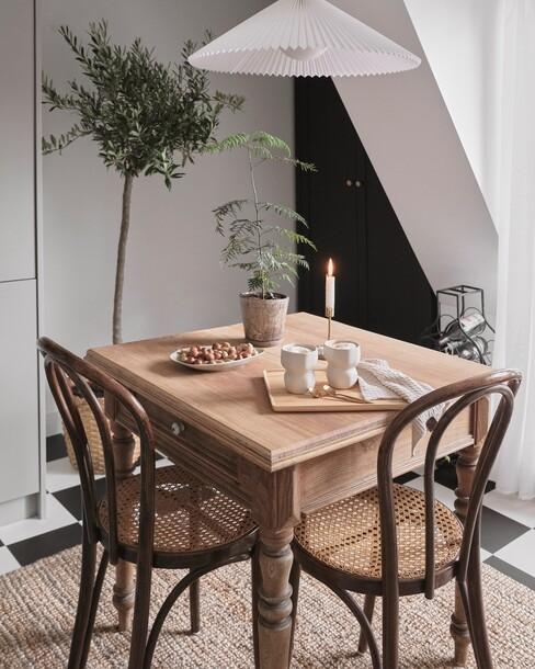 Witte lamp boven eettafel met houten stoelen