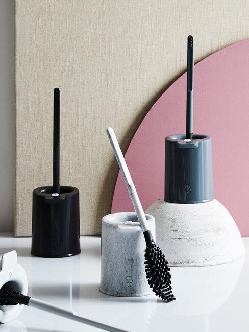 drie toiletborstels met roze achtergrond