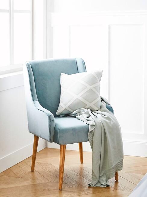 lichtblauwe fluwelen stoel met wit kussen en blauwe plaid