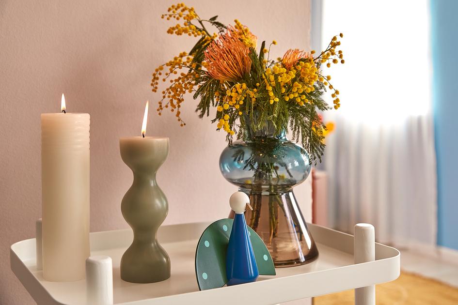 boeket bloemen in blauwe vaas en kaarsen op bijzettafel