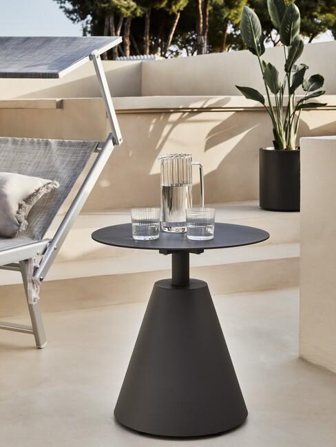 Grijze ronde tafel met een zwarte plantenbak