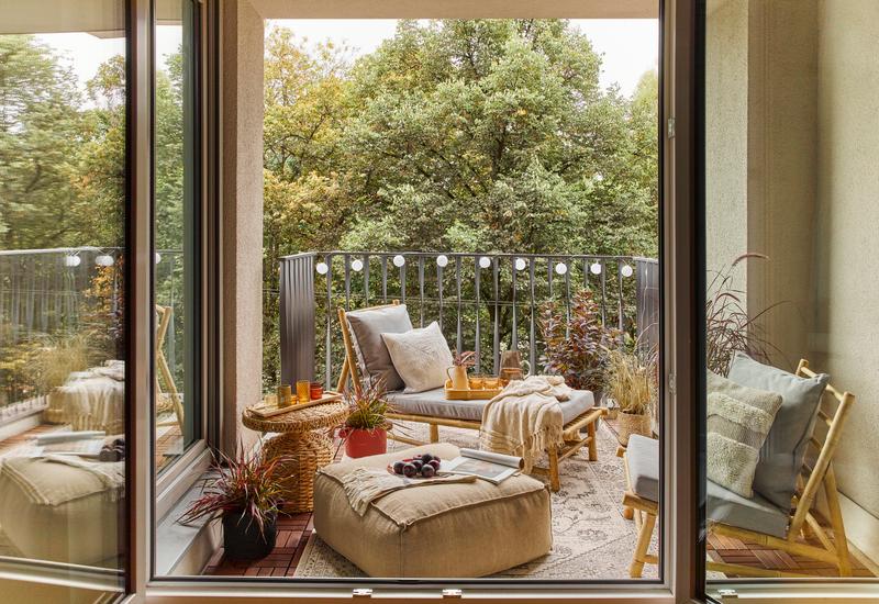 een gezellig balkon in boho stijl met lichtslingers, planten en plaids