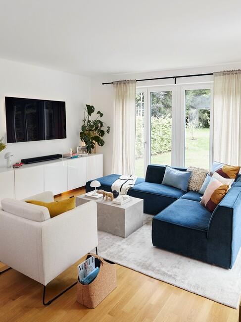 tv aan de muur met een wit dressoir met kamerplanten eronder