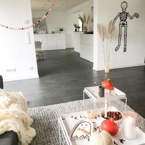 woonkamer versierd voor halloween met een skelet op de muur en pompoenen op de salontafel