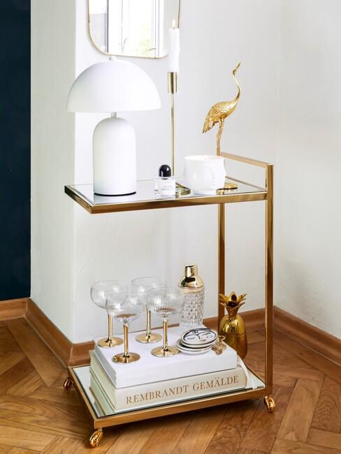 barkart met witte lamp, glazen en decoratieve boeken