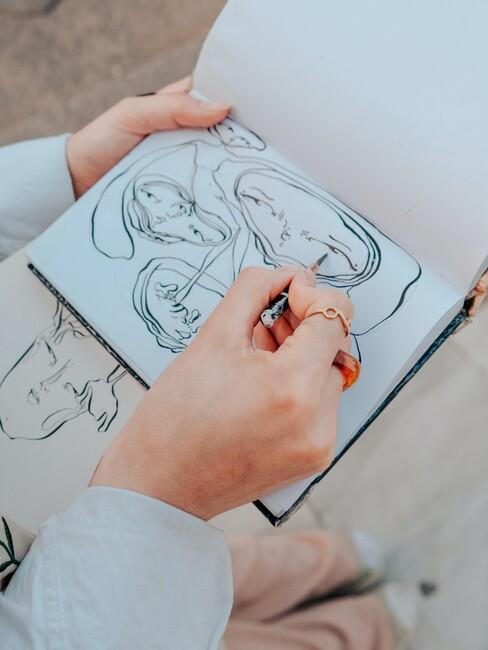 een cartoon tekening in een schetsboek die vastgehouden wordt