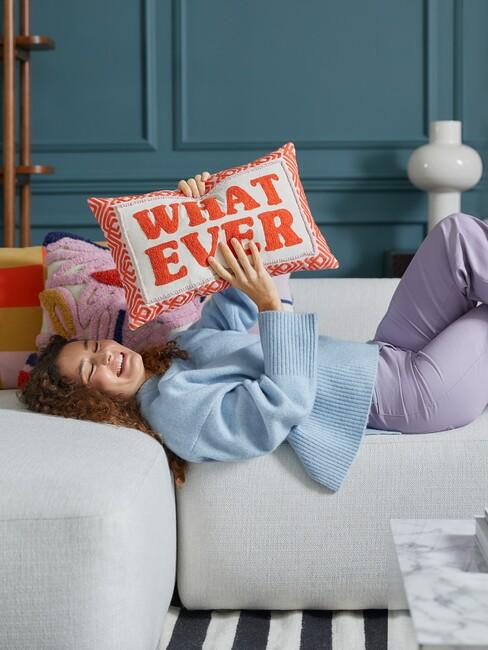 vrouw houdt kussen what ever vast op bank