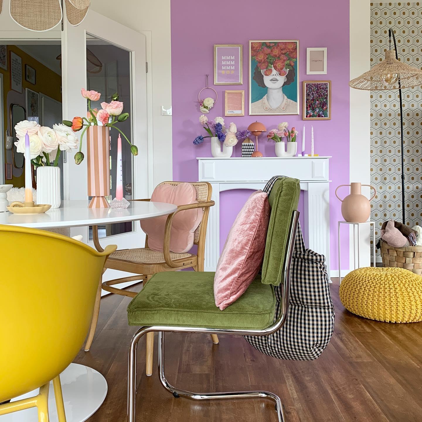 paarse muur in eetkamer met stoelen in okergeel en groen