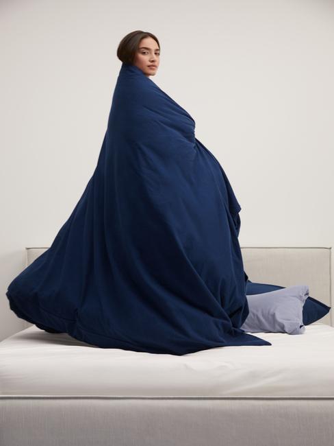 vrouw heeft nachtblauw dekbed omgeslagen