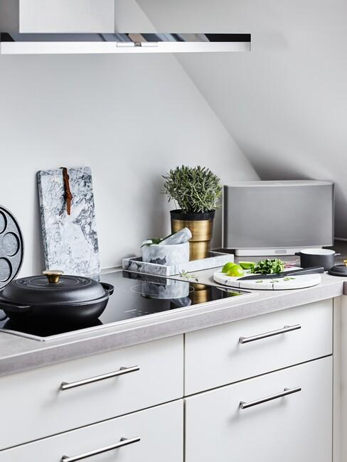 Kuchnia na poddaszku z białymi frontami szafek oraz akcesoriami