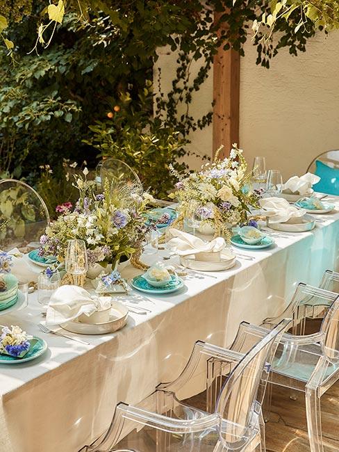 stoł w ogrodzie zastawiony pastelowymi kolorami w odcieniach niebieskiego i bieli