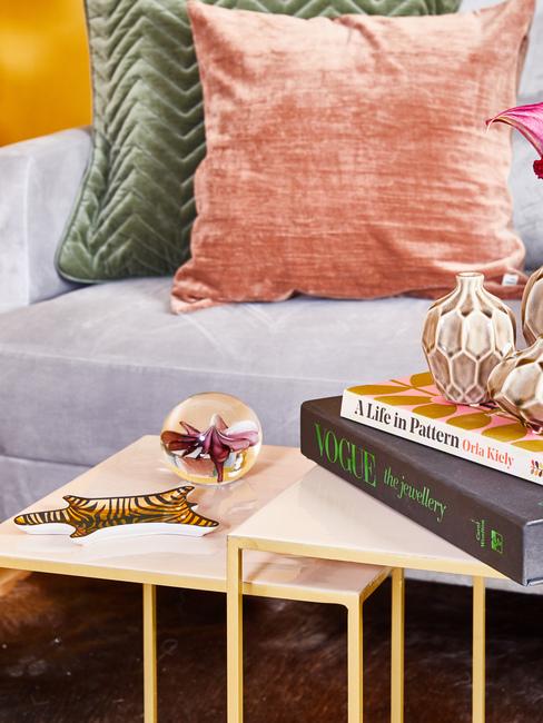 Zbliżenie na szarą sofę z szmaragdowozieloną i łososiową poduszka