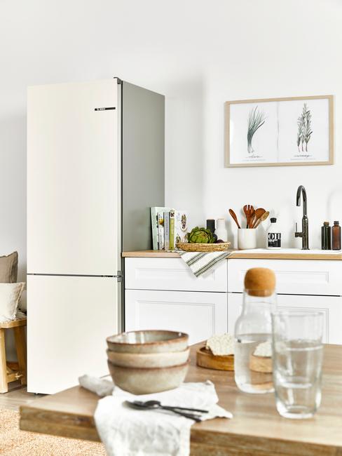 Białą kuchnia z lodówką, drewnianym blatem oraz stołem
