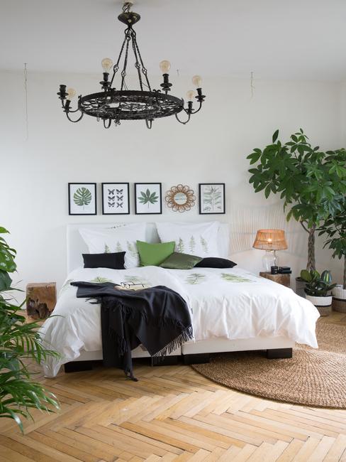 Jasna sypialnia z łóżkiem rozmiaru king size, roślinami i mosiężnym żyrandolem
