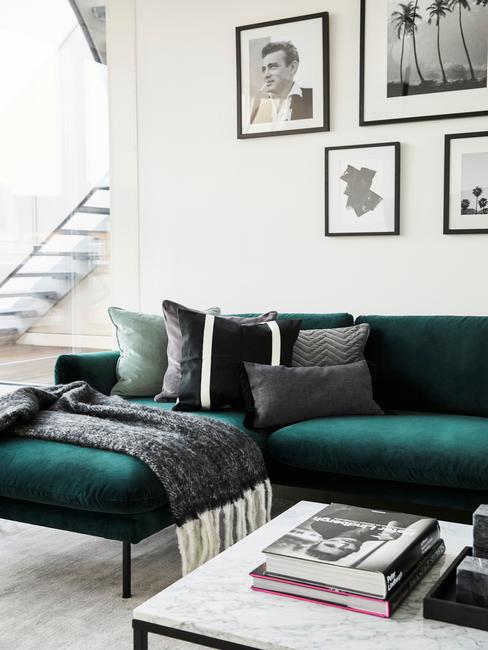 Szmaragdowa sofa, marmurowy stolik i czarno-białe fotografie