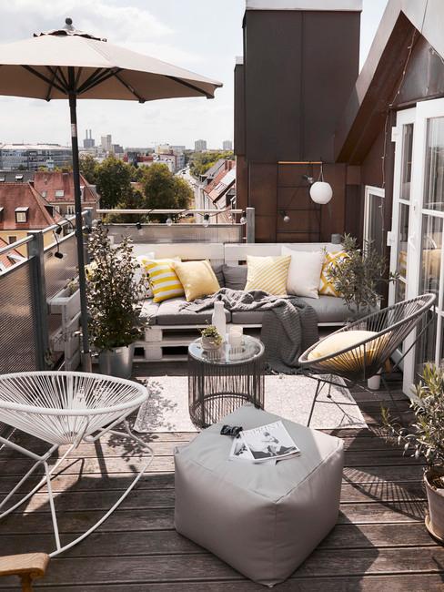 Balkon w mieście z krzesłami w różnych stylach oraz ławką zrobioną z plaet i dekoracjami