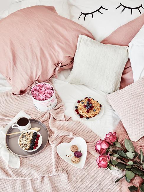 Łóżko z różowym kocem, różowymi poduszkami oraz białymi poduszkami