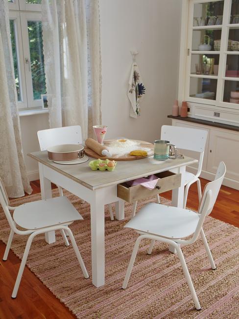 Fragment jadalni z białym stołem, czterema krzesłami oraz dywanem