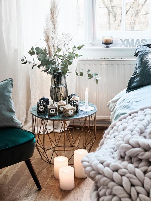 Fragment sypialni z łóżkiem z kocem pledowym, stolikiem kawowym z wazonem oraz krzesłem