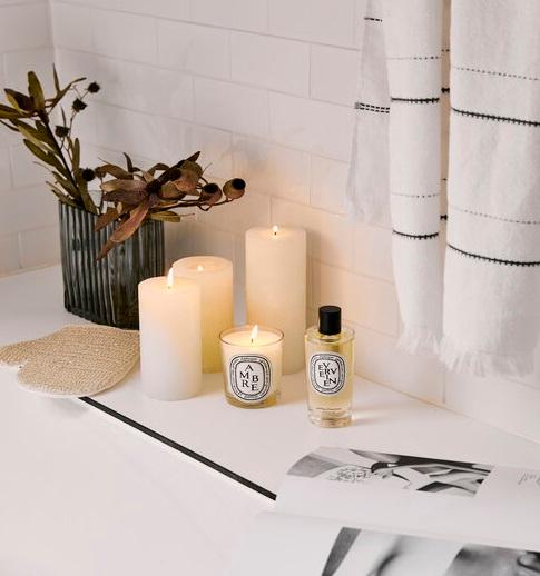 Świeczki ustawione na półce w białej łazience