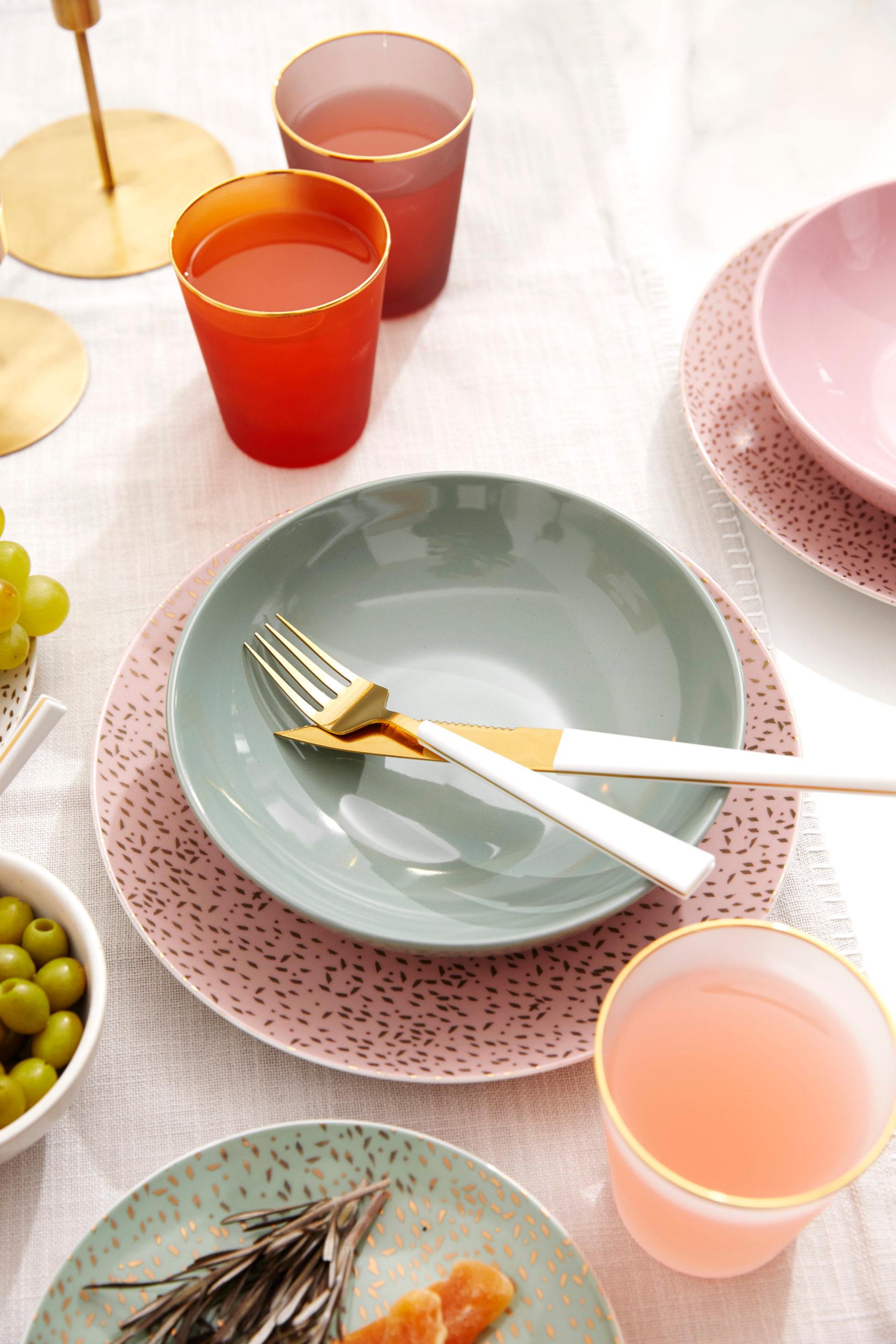 Różowy talerz oraz zielona miska ustawione na zastawionym stole