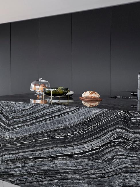 Czarna kuchnia z szafkami oraz blatem kuchennym wykonanym z czarnego marmuru